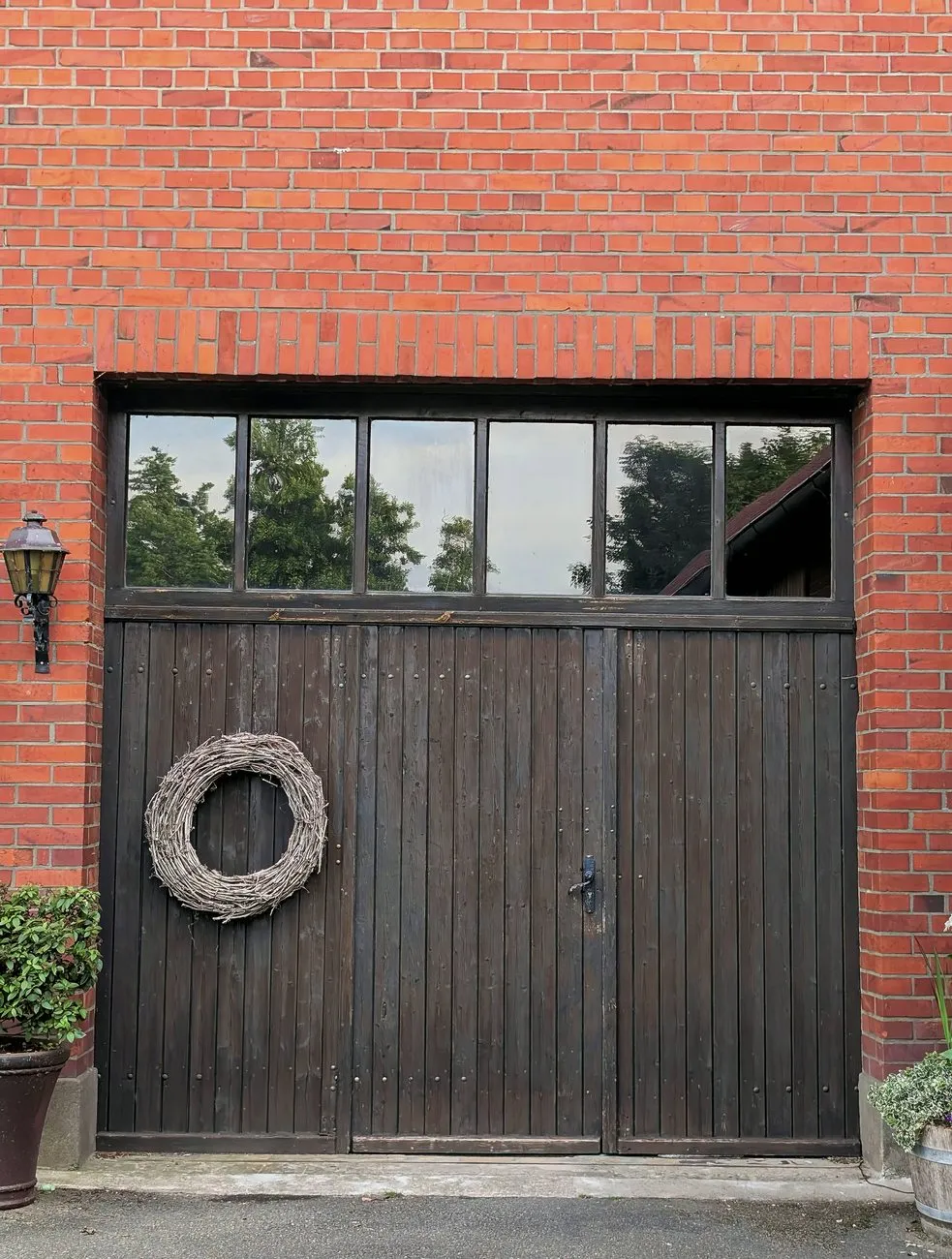 A pair of dark stained timber side-hinged doors with a glazed panel above, in a red brick wall